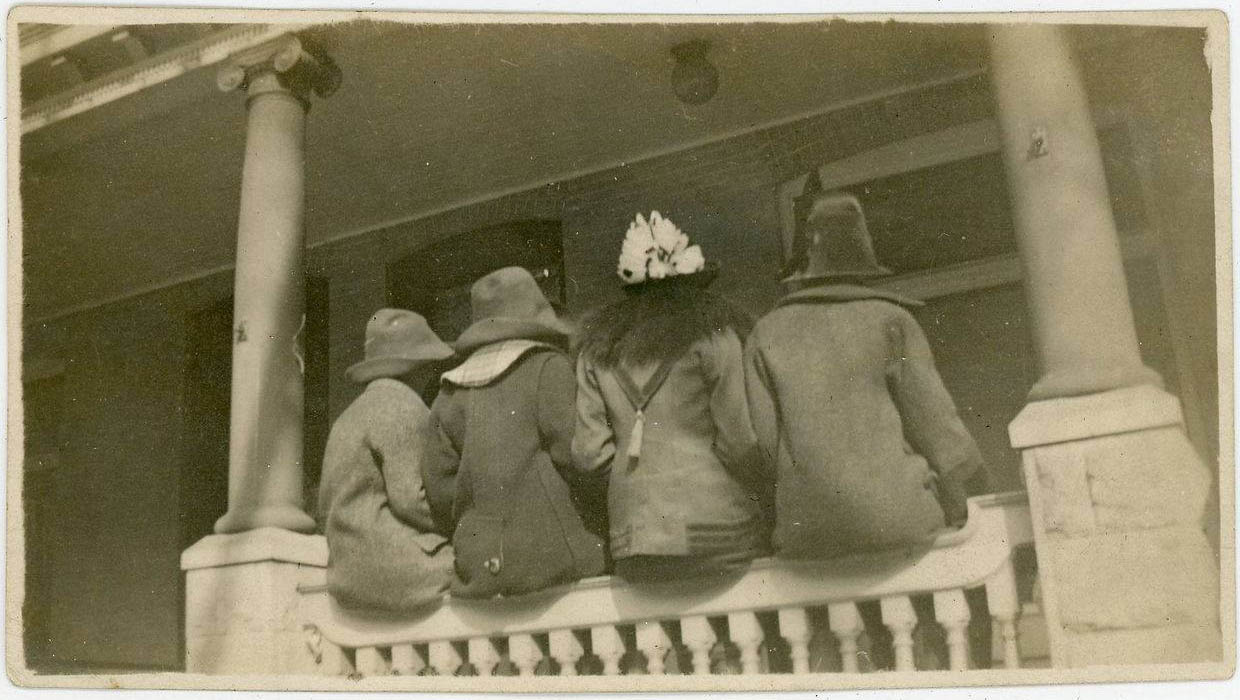 Group of people on a porch, sitting on railings, undated. | src eBay