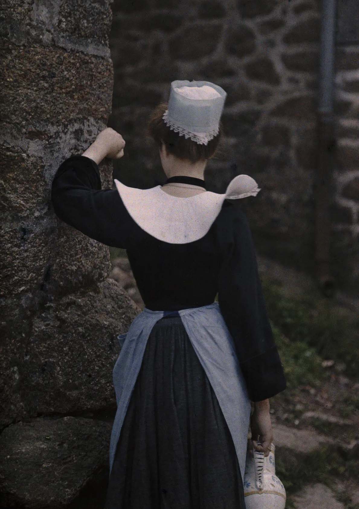 Jules Gervais-Courtellemont :: A woman in Brittany, France, leans against a stone wall in this early 1923. Autochrome. This image was featured in a 2010 exhibition of National Geographic's autochromes. | Nat Geo