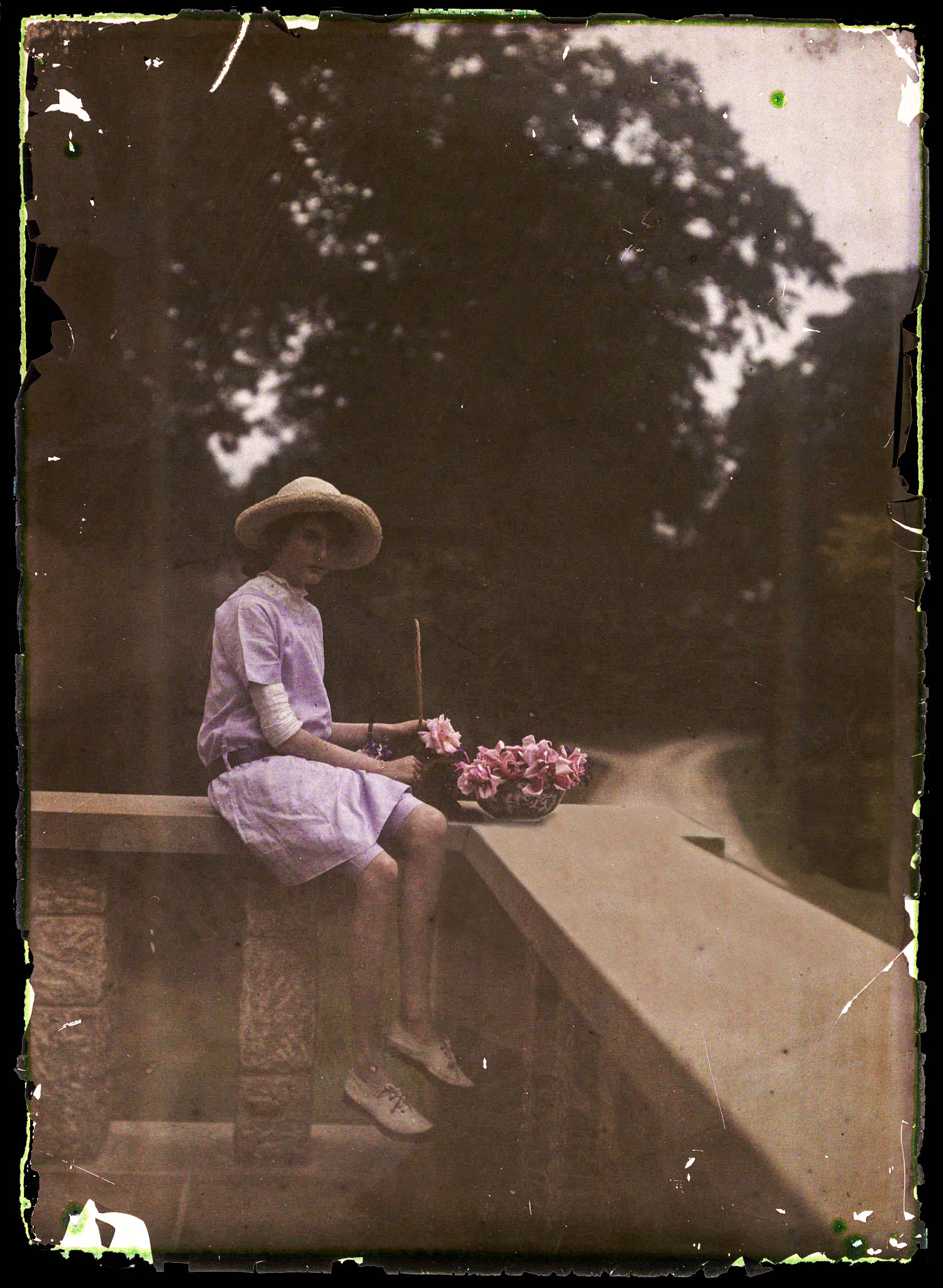 Etheldreda Janet Laing :: An Autochrome of a young girl sitting on a balcony next to a bowl of flowers, taken about 1910. The young girl, her faced shadowed by her straw bonnet, is possibly one of Janet Laing's daughters. | Getty Images